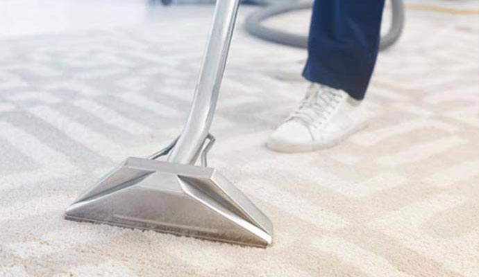 Person cleaning carpet with equipment