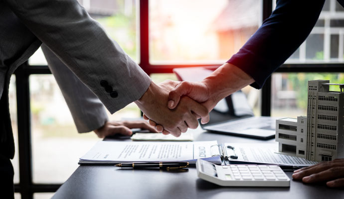 Professionals shaking hands over a contract on a desk