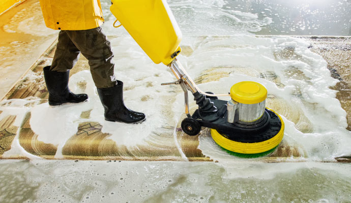 A person cleaning a rug with a machine