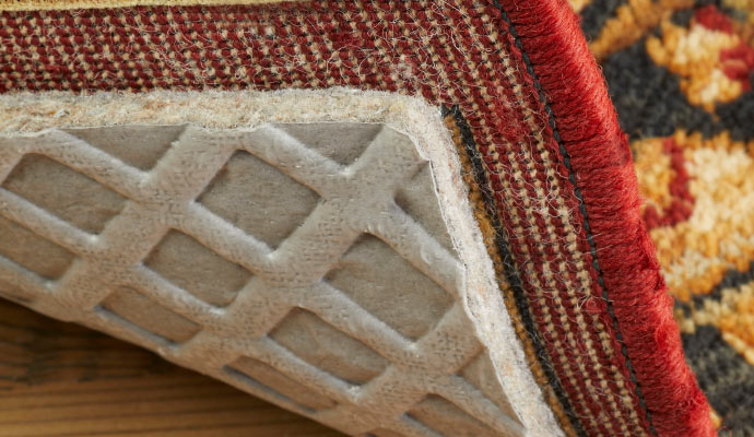 A rug showing the corner with the rug pad underneath