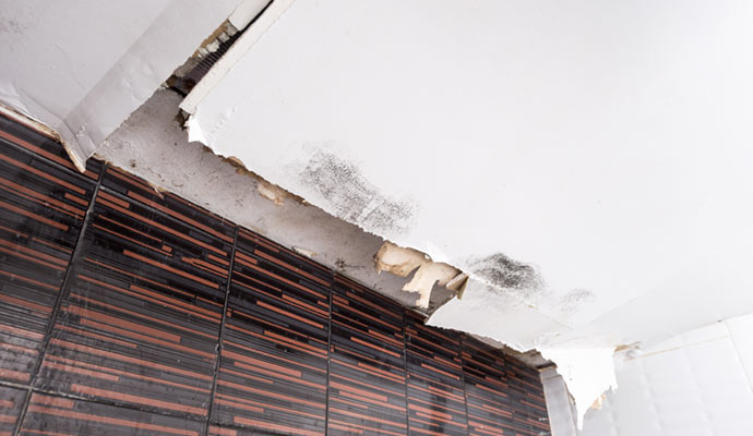 A ceiling with visible water damage, showing stains, discoloration, and potential structural issues.